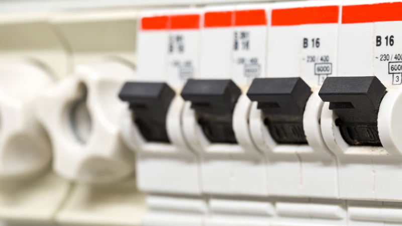 close up of black switches on white fuse board with red labels above