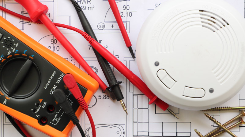 fire alarm and electrical testing kit on top of electrical plans for building